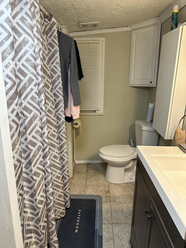 bathroom featuring tile patterned floors, vanity, a textured ceiling, and toilet