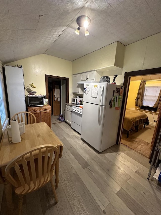 kitchen with light hardwood / wood-style flooring, vaulted ceiling, a textured ceiling, white appliances, and white cabinets