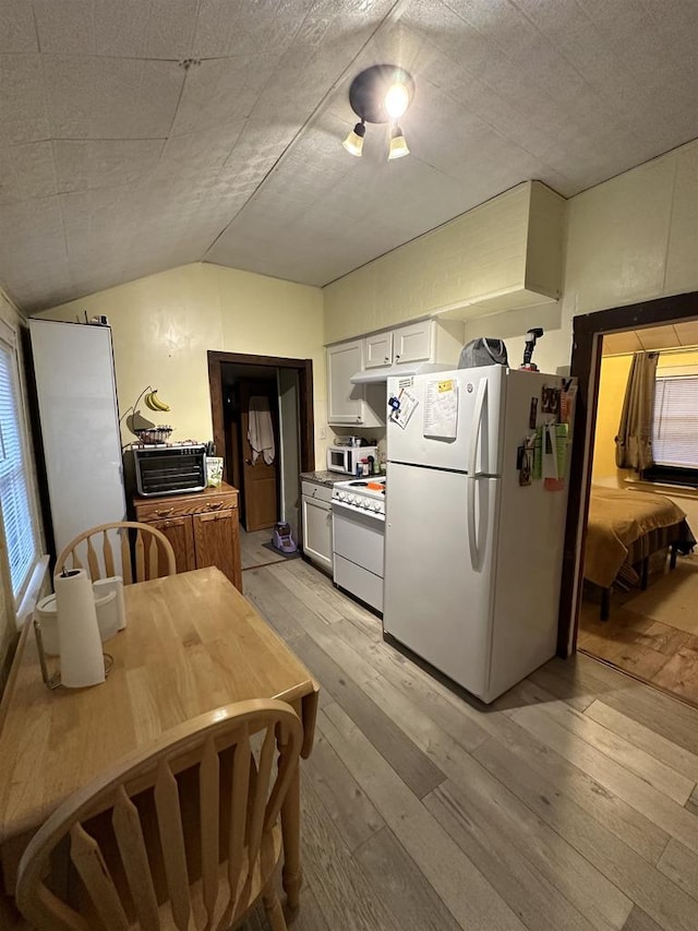 kitchen featuring white cabinets, light wood-type flooring, white appliances, and vaulted ceiling