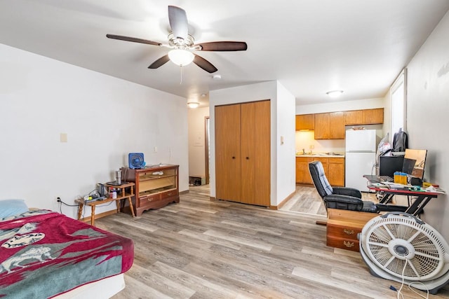 bedroom featuring sink, ceiling fan, light hardwood / wood-style floors, white fridge, and a closet