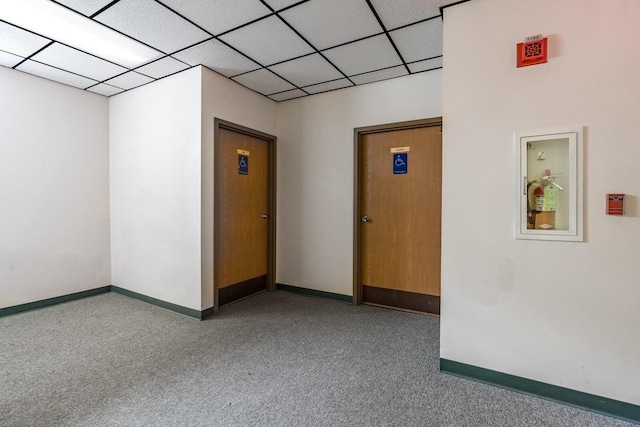 carpeted empty room with a drop ceiling