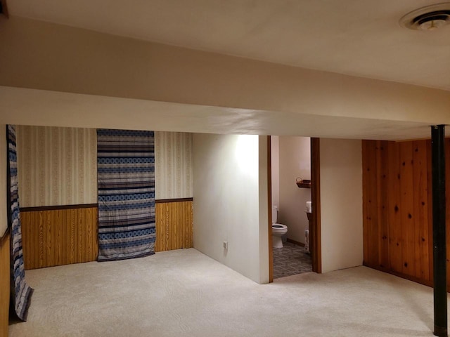 basement with carpet flooring and wood walls