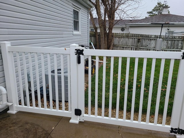 view of gate featuring central air condition unit and a yard