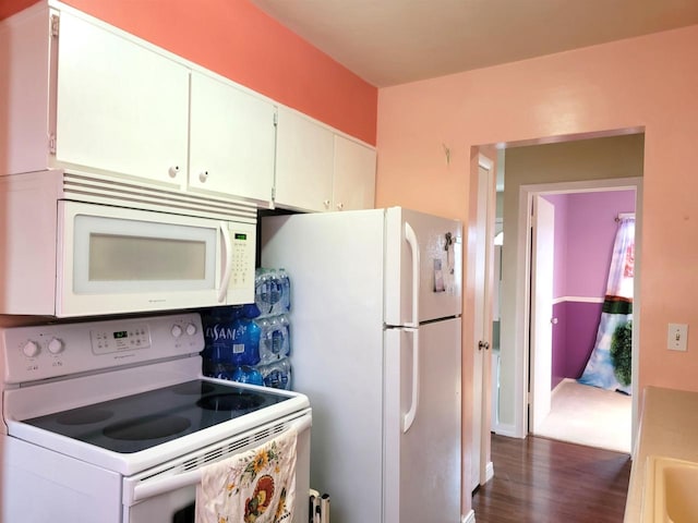 kitchen with white cabinets, dark hardwood / wood-style floors, and white appliances