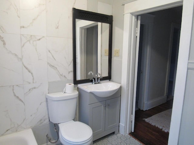 bathroom featuring toilet, wood-type flooring, vanity, and a bathtub