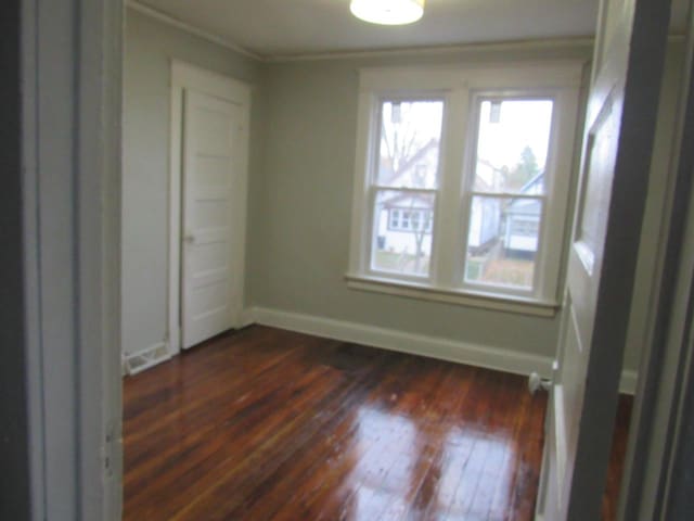 unfurnished bedroom featuring ornamental molding and dark hardwood / wood-style flooring