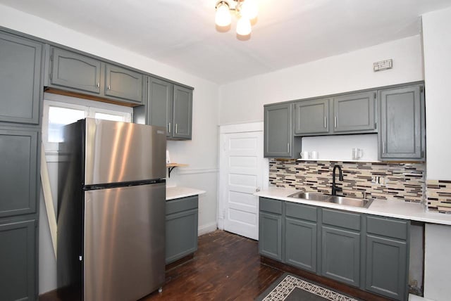 kitchen with tasteful backsplash, gray cabinets, dark hardwood / wood-style flooring, stainless steel refrigerator, and sink