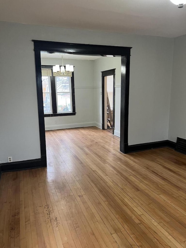 empty room with a chandelier and light hardwood / wood-style floors