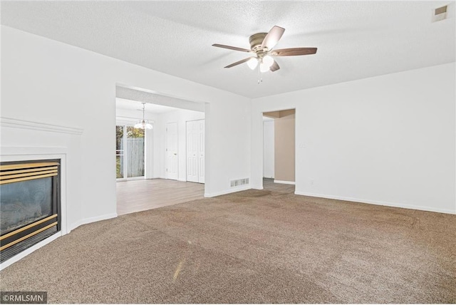 unfurnished living room with carpet flooring, ceiling fan with notable chandelier, and a textured ceiling