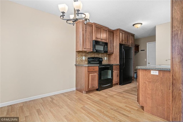 kitchen with backsplash, a chandelier, black appliances, and light wood-type flooring