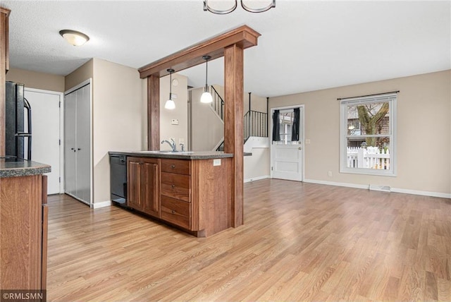 kitchen featuring refrigerator, sink, hanging light fixtures, black dishwasher, and light hardwood / wood-style floors