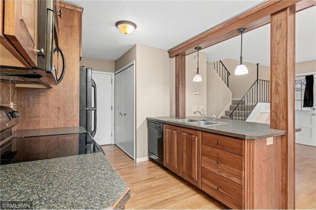 kitchen featuring sink, hanging light fixtures, a textured ceiling, black appliances, and light wood-type flooring