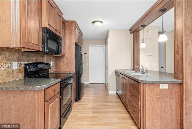 kitchen featuring sink, decorative light fixtures, decorative backsplash, black appliances, and light wood-type flooring