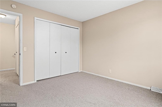 unfurnished bedroom featuring light colored carpet and a closet