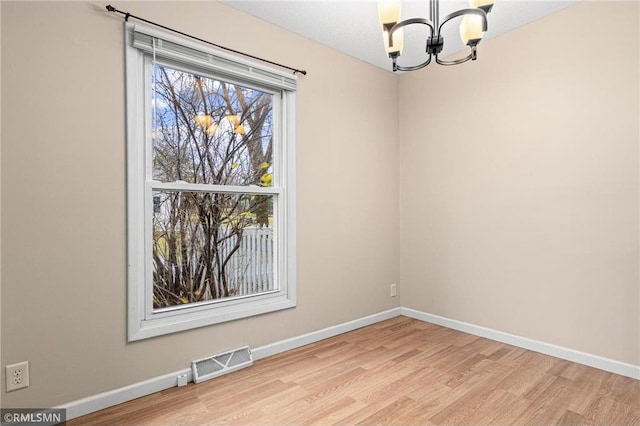 unfurnished room featuring a chandelier and light wood-type flooring