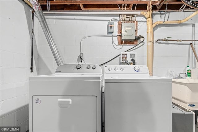 clothes washing area featuring independent washer and dryer, electric panel, and sink