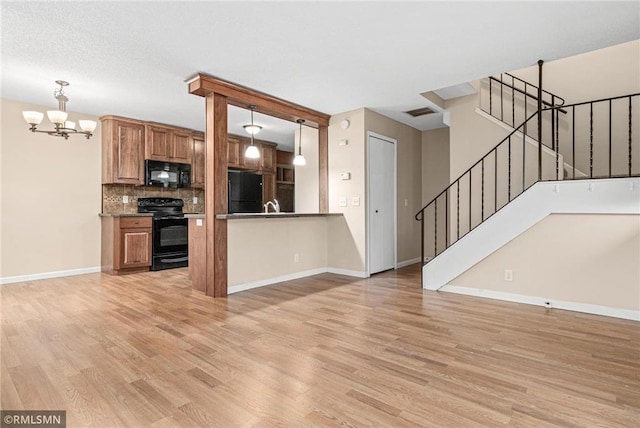 kitchen featuring hanging light fixtures, an inviting chandelier, light hardwood / wood-style flooring, decorative backsplash, and black appliances