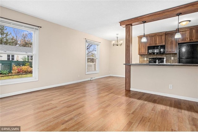 kitchen with black appliances, hanging light fixtures, tasteful backsplash, a notable chandelier, and light hardwood / wood-style floors