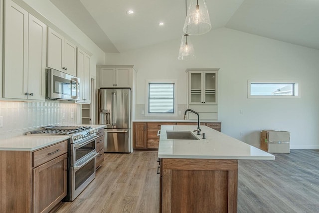 kitchen with pendant lighting, high quality appliances, lofted ceiling, light wood-type flooring, and white cabinetry