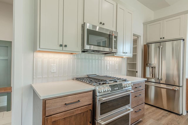 kitchen with decorative backsplash, light hardwood / wood-style floors, white cabinets, and high end appliances