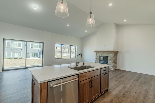 kitchen featuring dishwasher, a center island with sink, sink, light hardwood / wood-style flooring, and vaulted ceiling