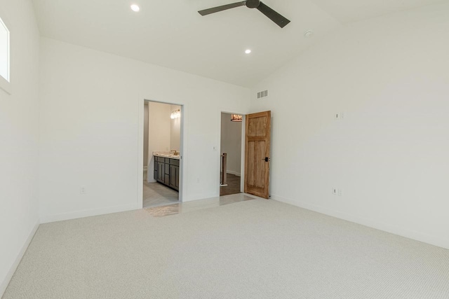 unfurnished bedroom featuring ensuite bath, ceiling fan, high vaulted ceiling, and light colored carpet