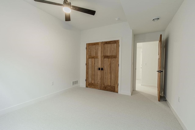 unfurnished bedroom featuring light carpet, a closet, and ceiling fan