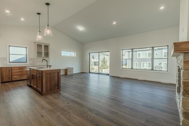 kitchen featuring sink, dark wood-type flooring, high vaulted ceiling, an island with sink, and decorative light fixtures