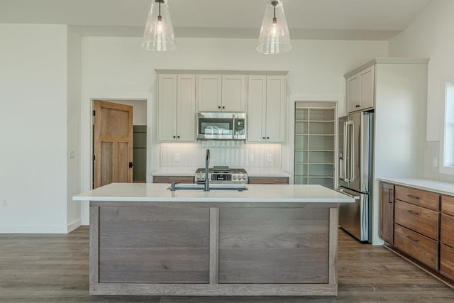 kitchen featuring white cabinets, wood-type flooring, stainless steel appliances, and hanging light fixtures