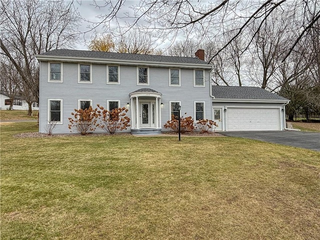 colonial-style house featuring a garage and a front lawn