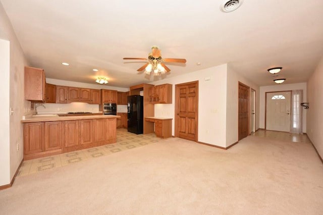 kitchen featuring black refrigerator, sink, kitchen peninsula, and light carpet