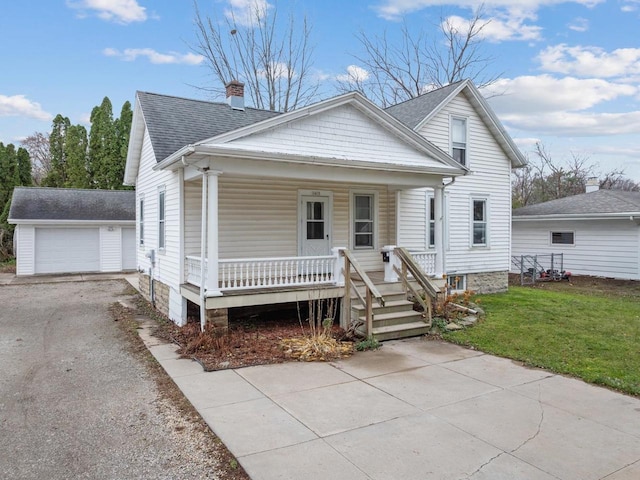 bungalow featuring a front yard, covered porch, an outdoor structure, and a garage