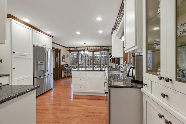 kitchen featuring kitchen peninsula, pendant lighting, high end fridge, white cabinets, and light wood-type flooring