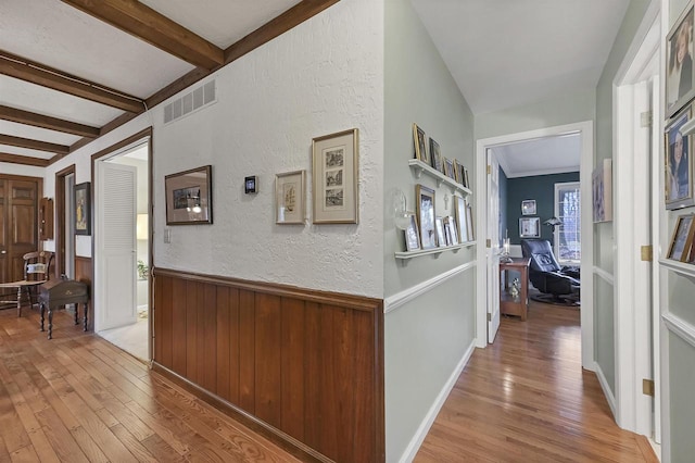 hallway featuring light hardwood / wood-style flooring and beamed ceiling