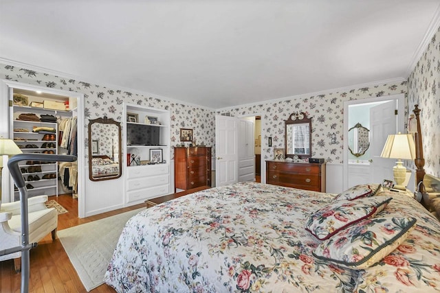 bedroom featuring hardwood / wood-style floors, a walk in closet, a closet, and crown molding