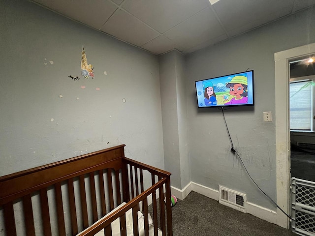 bedroom with a paneled ceiling, carpet floors, and a crib