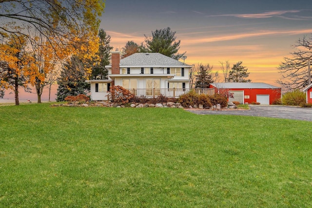 view of front of property featuring a yard, an outbuilding, covered porch, and a garage