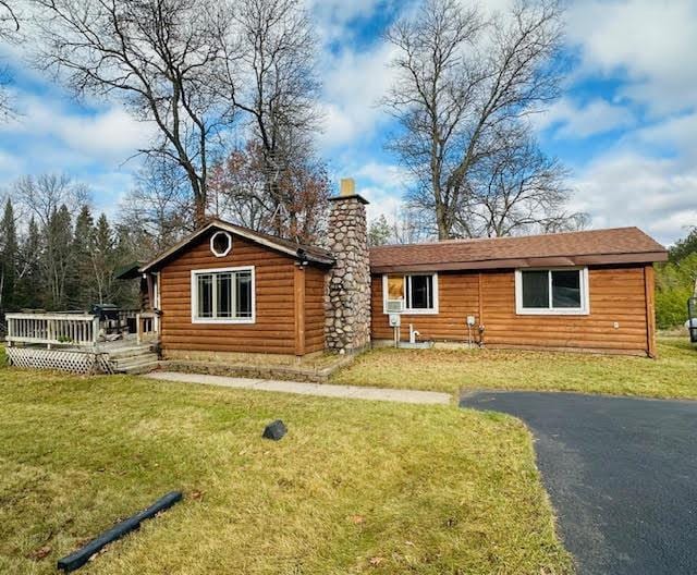 cabin with a deck and a front lawn