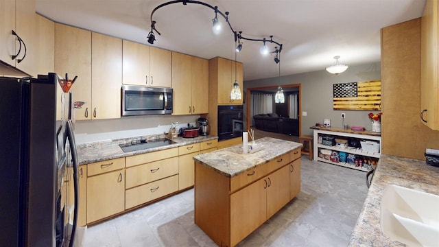 kitchen with a kitchen island, light brown cabinetry, decorative light fixtures, black appliances, and light stone countertops