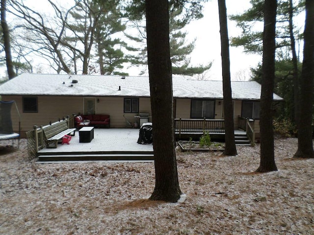 rear view of property featuring a trampoline, an outdoor living space, and a deck