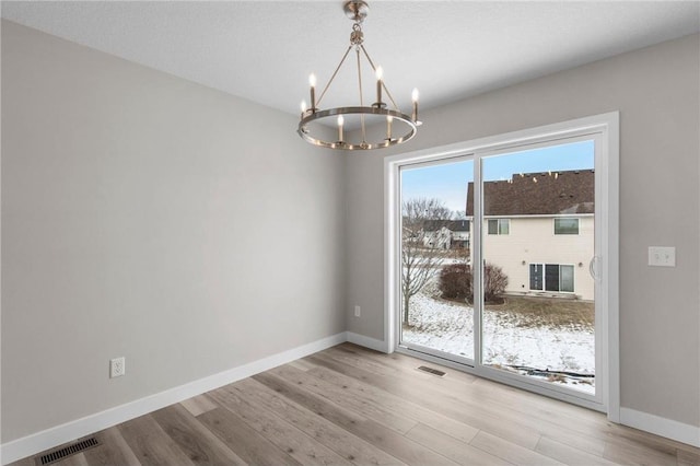 unfurnished dining area with an inviting chandelier and light hardwood / wood-style floors