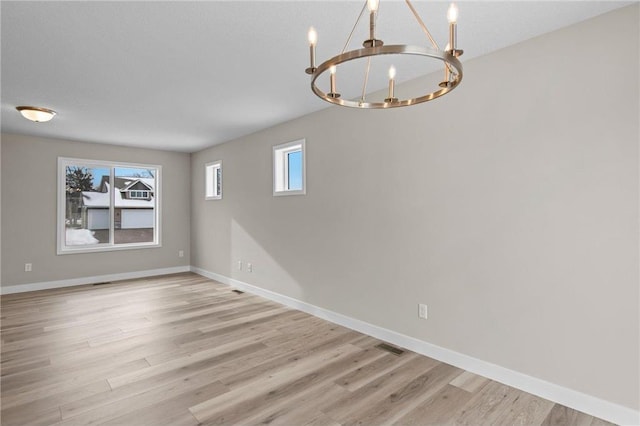 empty room with an inviting chandelier and light hardwood / wood-style floors