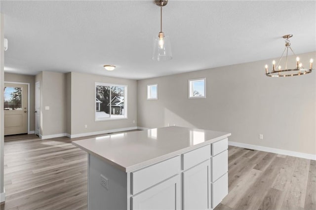 kitchen with white cabinetry, hanging light fixtures, a textured ceiling, and a kitchen island