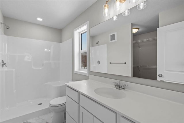 bathroom featuring a shower, vanity, and toilet