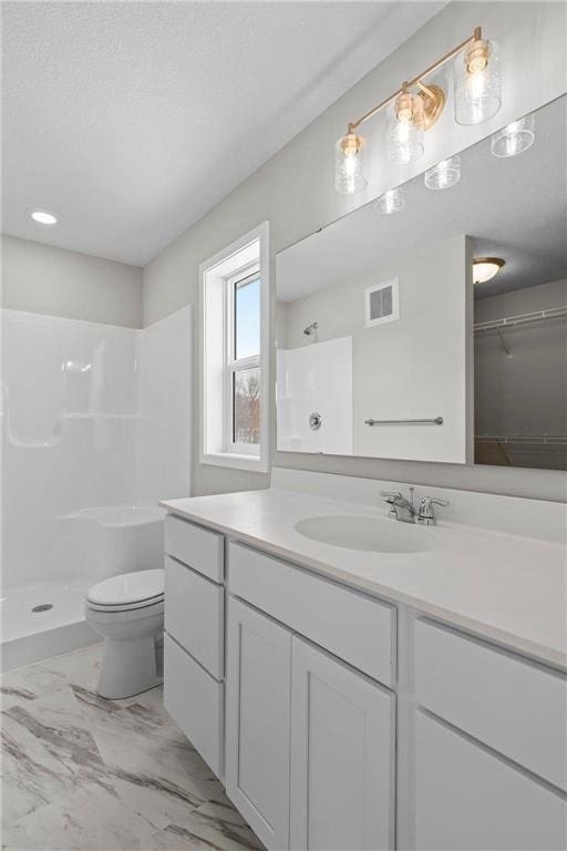 bathroom featuring vanity, a textured ceiling, toilet, and walk in shower