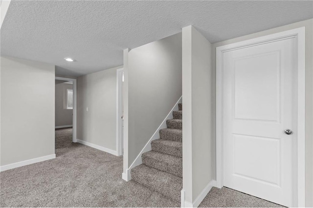 staircase featuring carpet floors and a textured ceiling