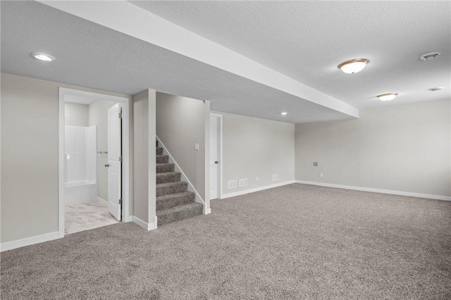 basement featuring light carpet and a textured ceiling