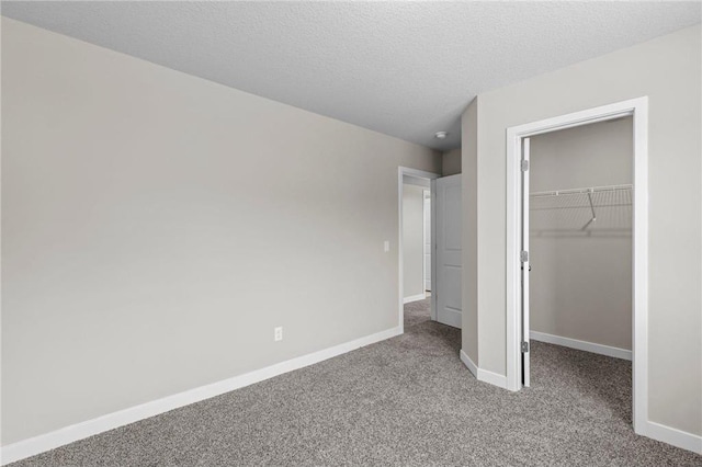 unfurnished bedroom with a walk in closet, carpet floors, a textured ceiling, and a closet