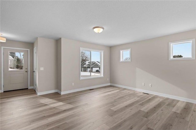 unfurnished room with light hardwood / wood-style floors and a textured ceiling