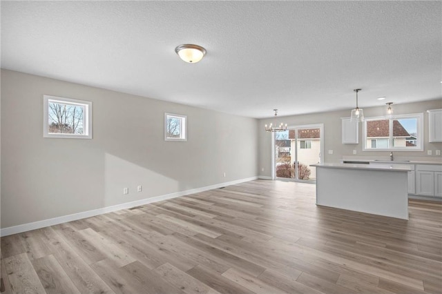 unfurnished living room featuring a healthy amount of sunlight, sink, and light hardwood / wood-style flooring